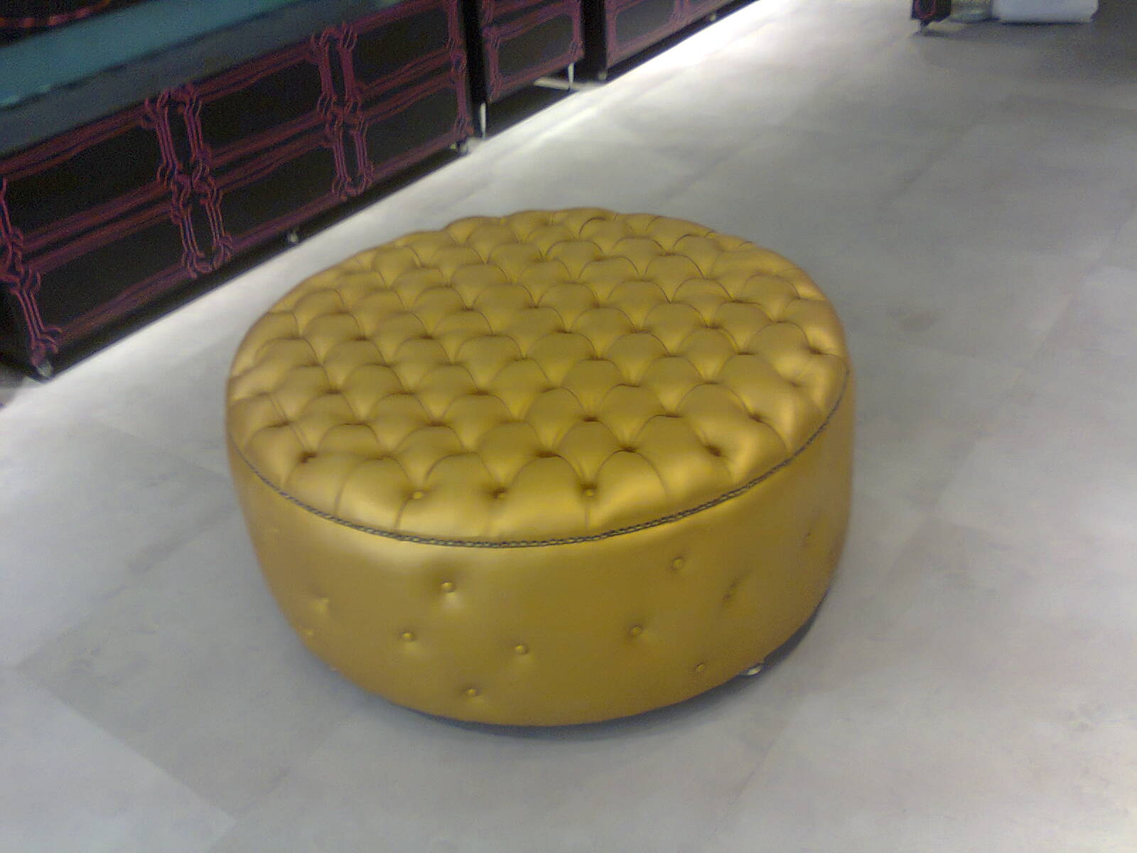 Pufe redondo grande com estofado em couro dourado e detalhes em capitonê
